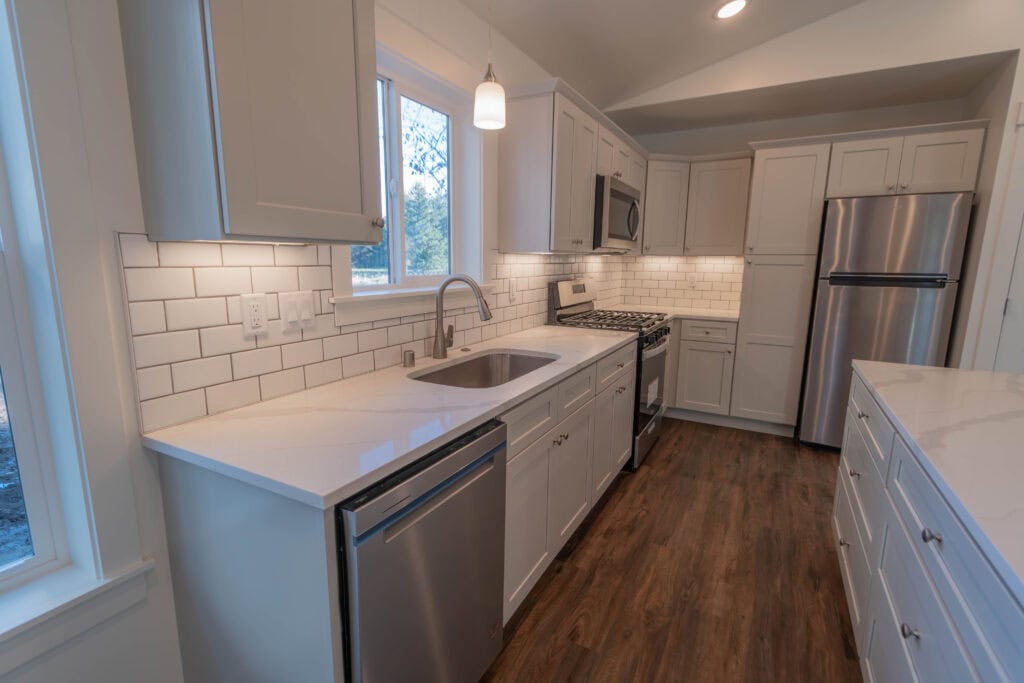 Kitchen in a Wolf Model J home with tile backsplash, island, and undermount sink.