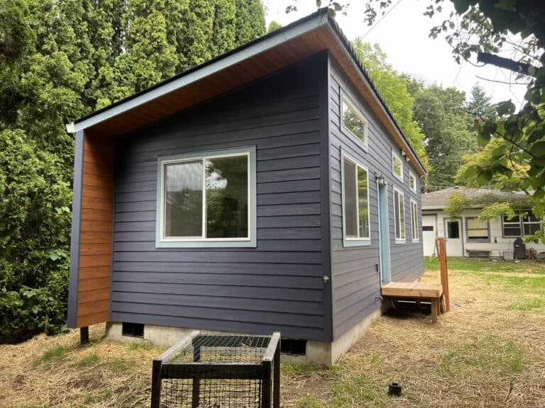 Blue-gray Wolf Model K home with a wood-sided gable end and a small wood step.