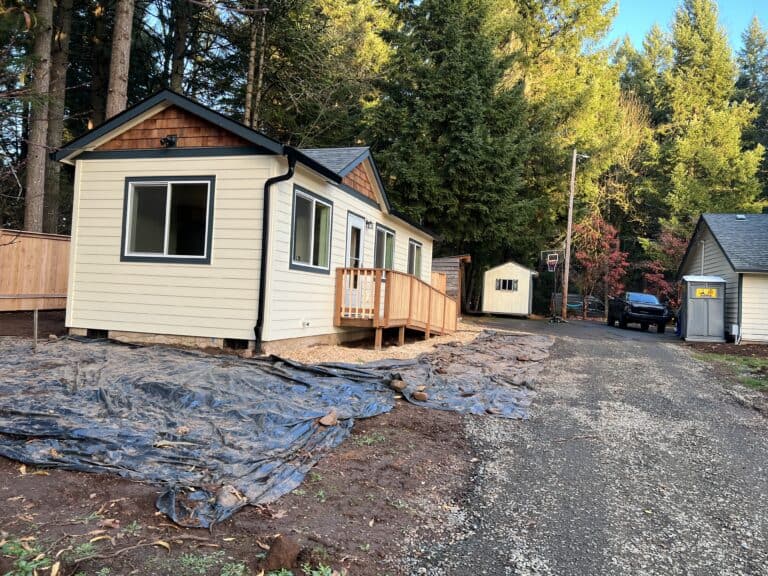 Cream Wolf Model K home with black trim, a cedar-shake gable, and a wood deck.