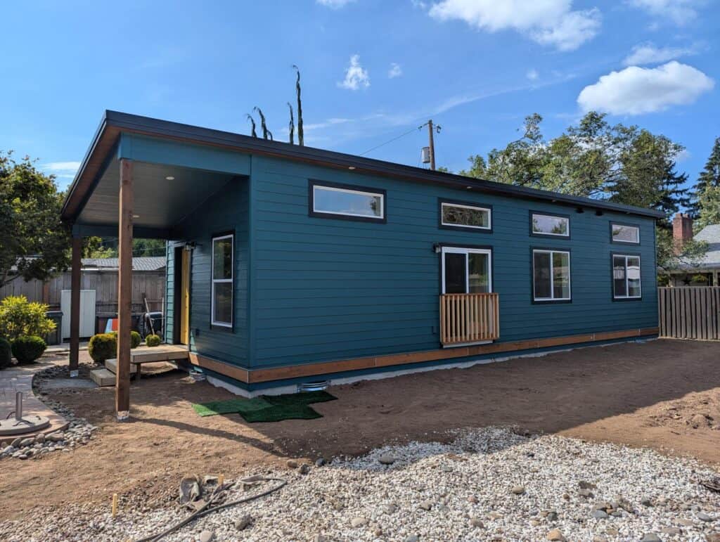 Green and black Wolf Model E home with covered porch and yellow door.