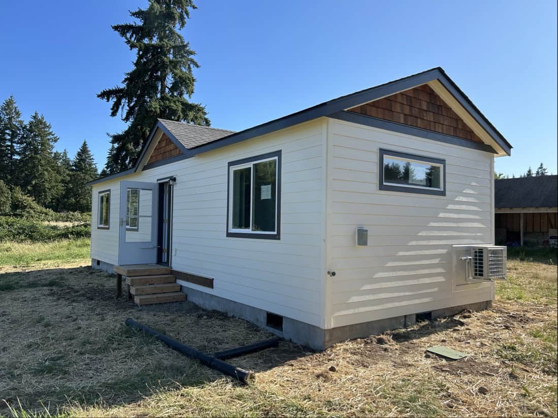 White and black Wolf Model E home with cedar shake gables and storm door.