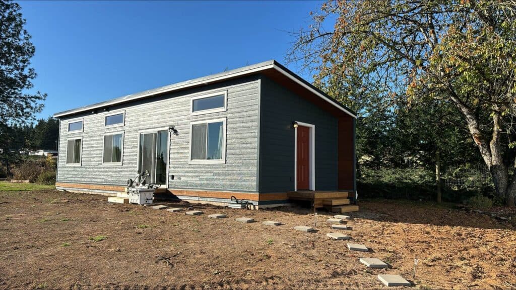 Green and white Wolf Model E home with red front door.