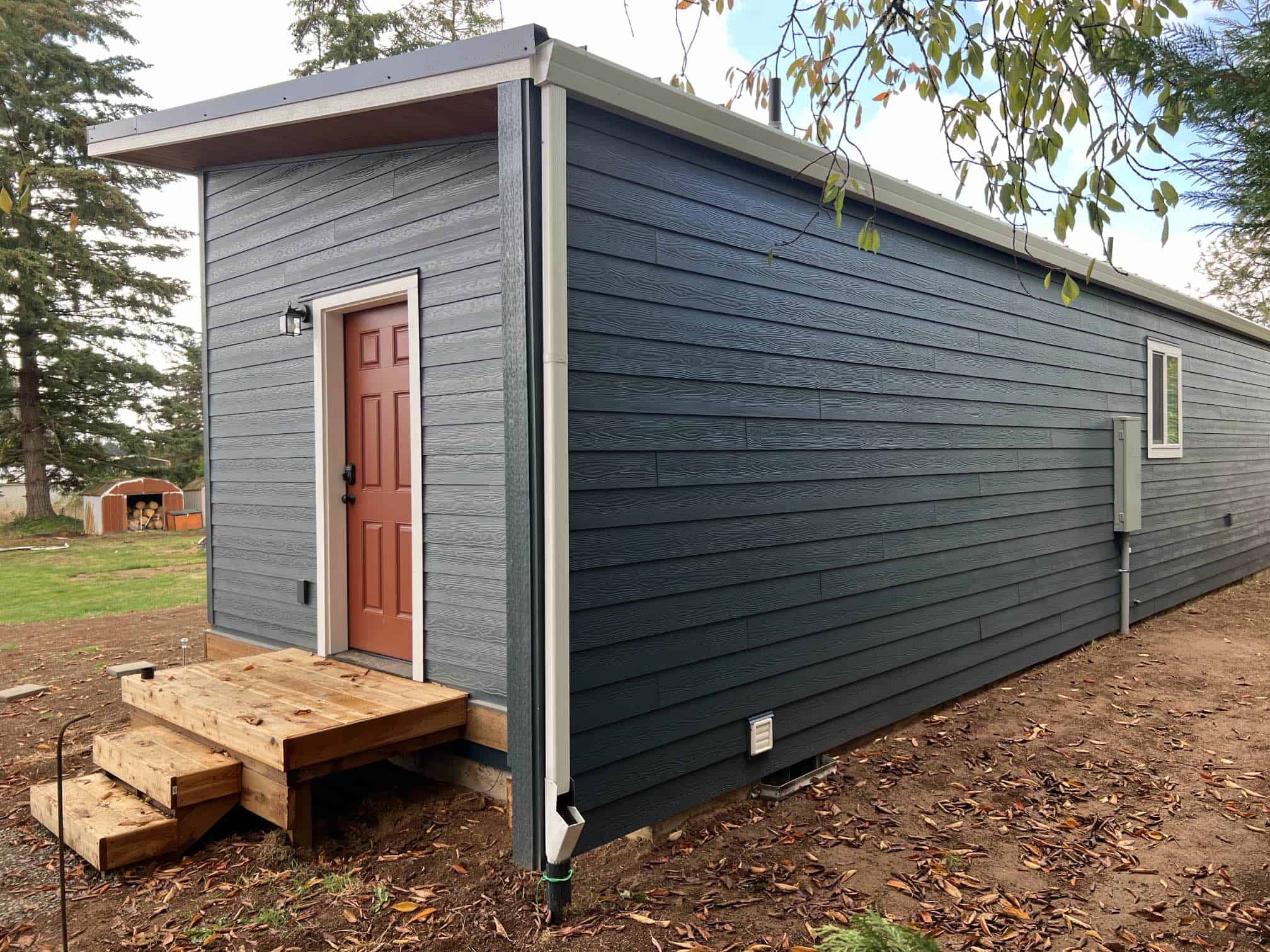 Green and white Wolf Model E home with red door.