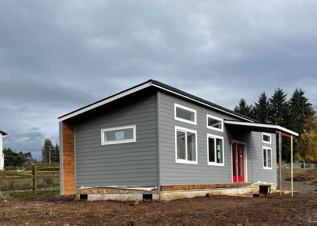 Grey and white Wolf Model E home with transom windows and red French doors.