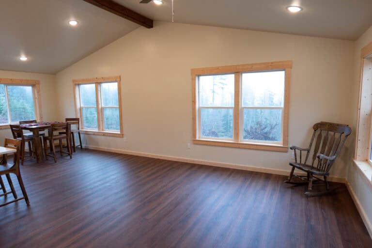 Vaulted living and dining room with a wood dining set and a rocking chair in a Wolf Model I home.