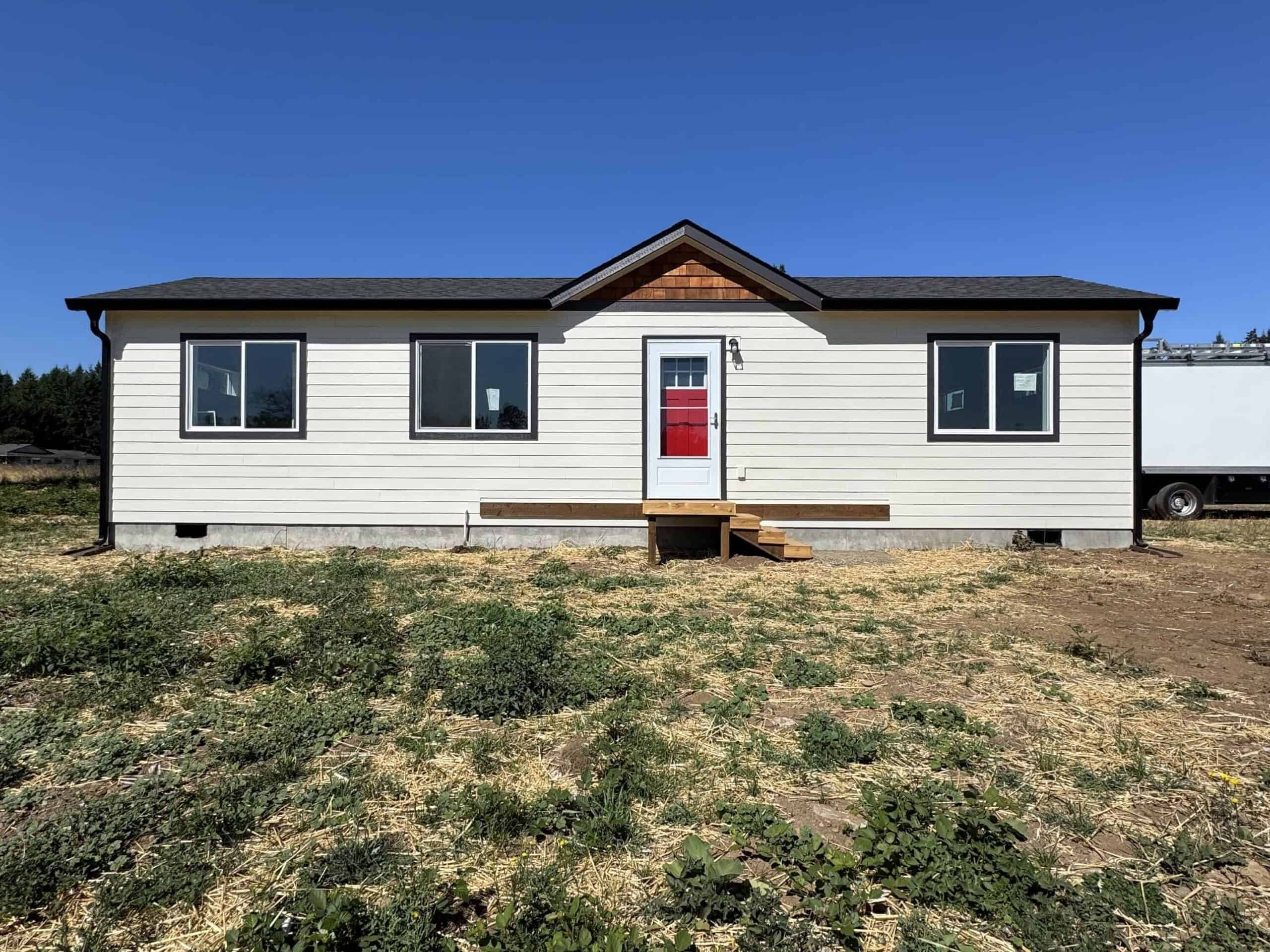White and black Wolf Model E home with red door and cedar shake gable.