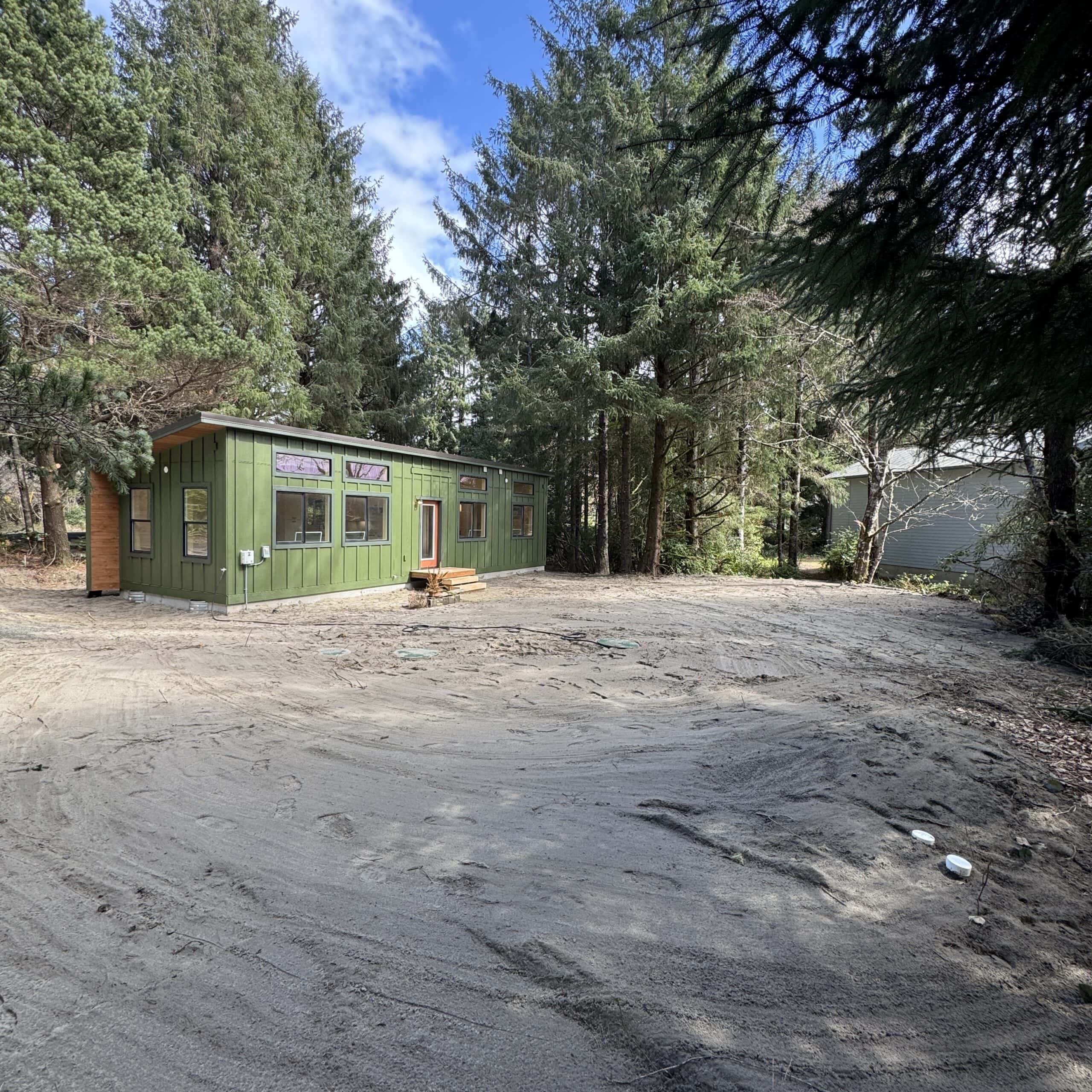 Green Wolf Model F home with board and batten siding, black vinyl windows, and a metal shed roof.