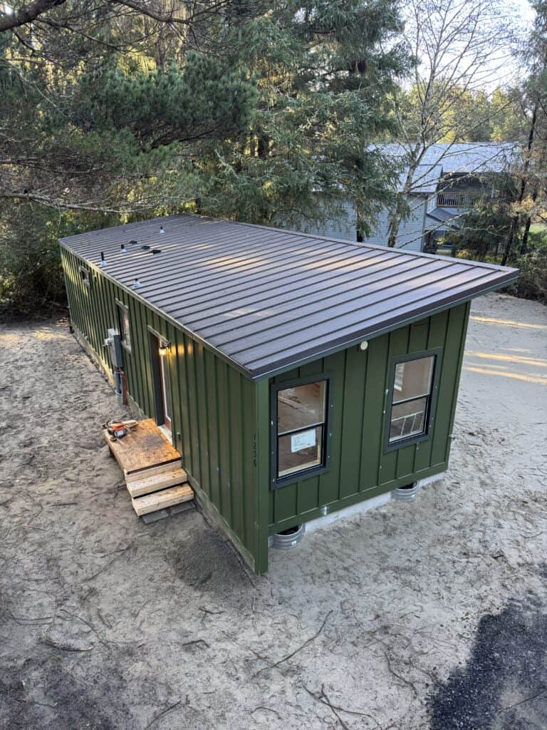 Green Wolf Model F home with board and batten siding and metal shed roof.