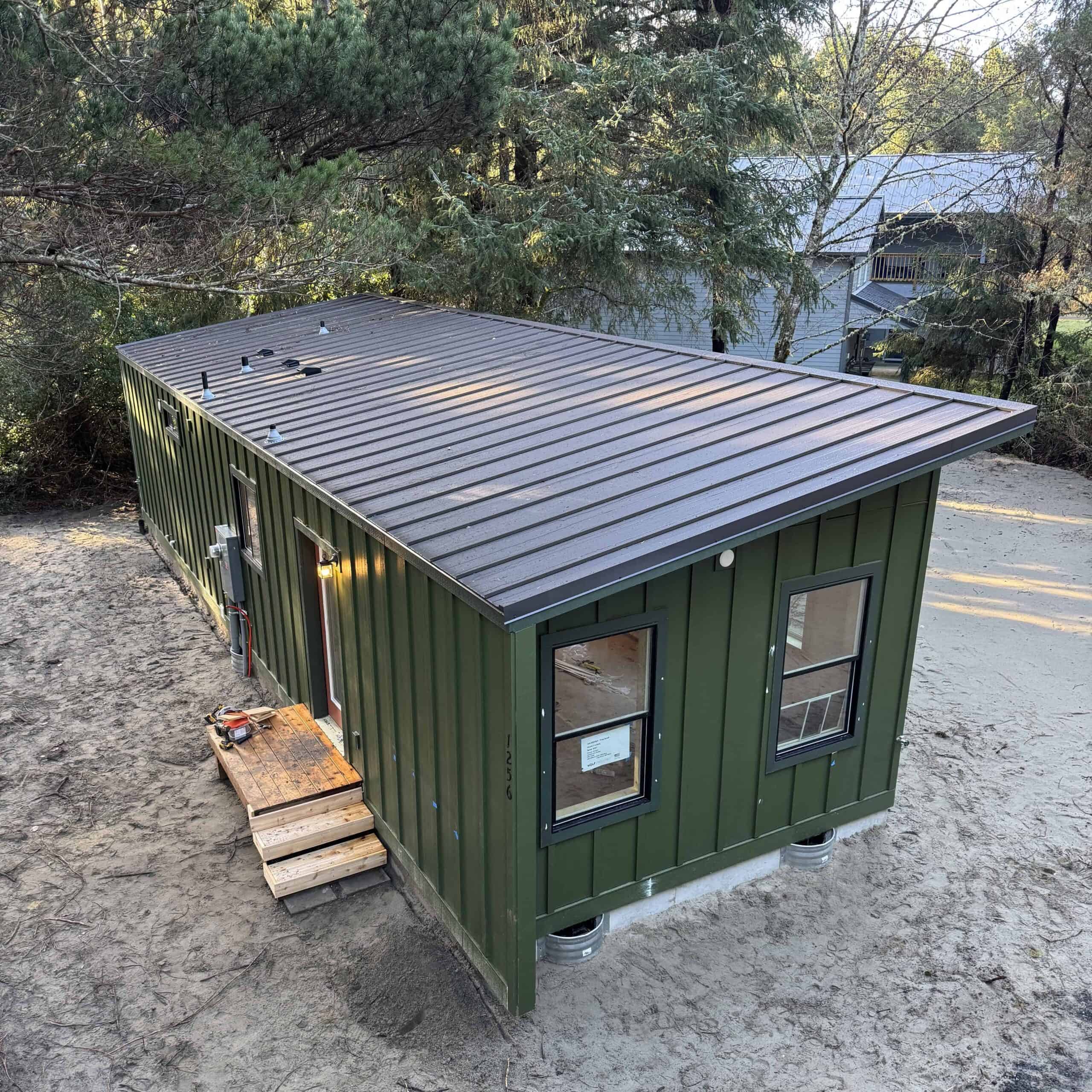 Green Wolf Model F home with board and batten siding and metal shed roof.