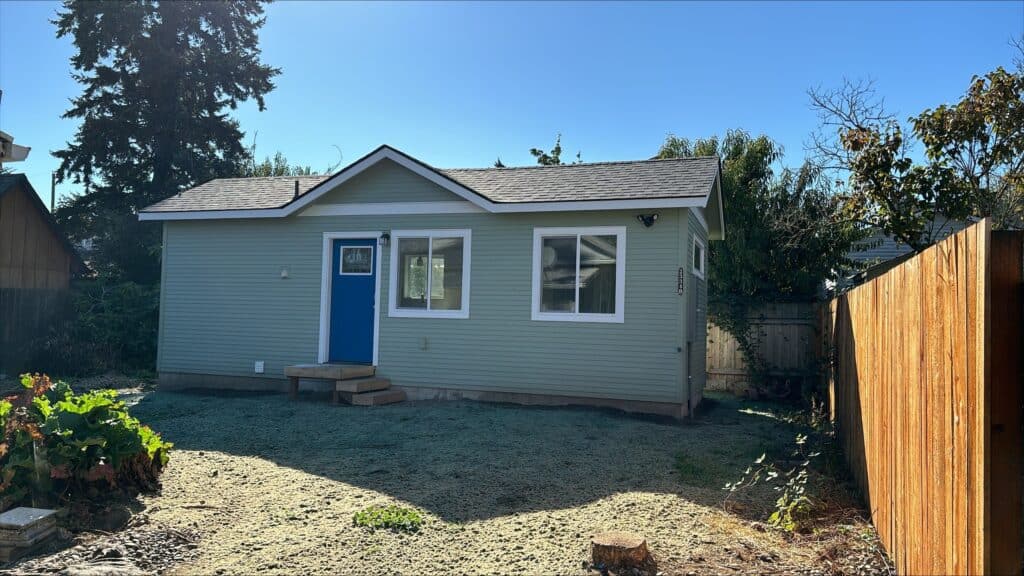 Green and white Wolf Model B tiny home with blue door.