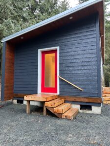 Blue Model E modular home with red door.